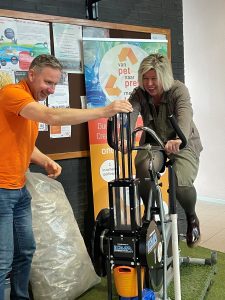 vrouw aan het trappen op een fiets om plastic flessen te persen zodat er kroonluchters van gemaakt kunnen worden