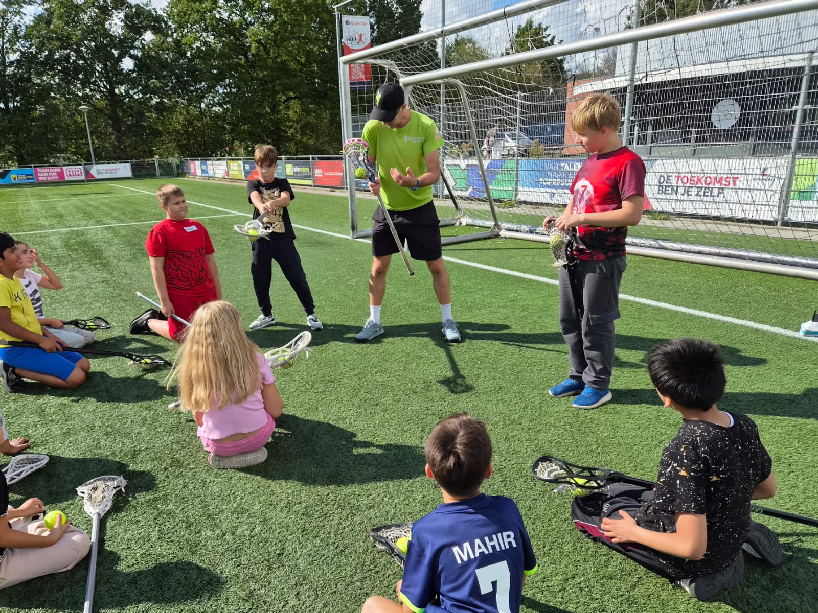lacrosse trainer legt uit aan kinderen hoe het spel werkt